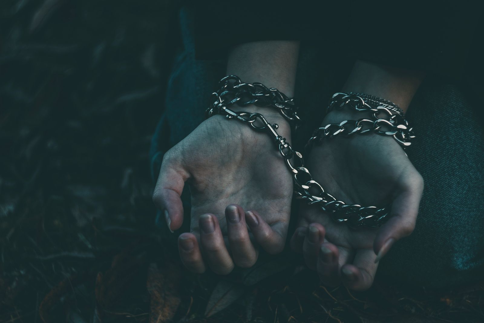Hands bound with chains in darkness