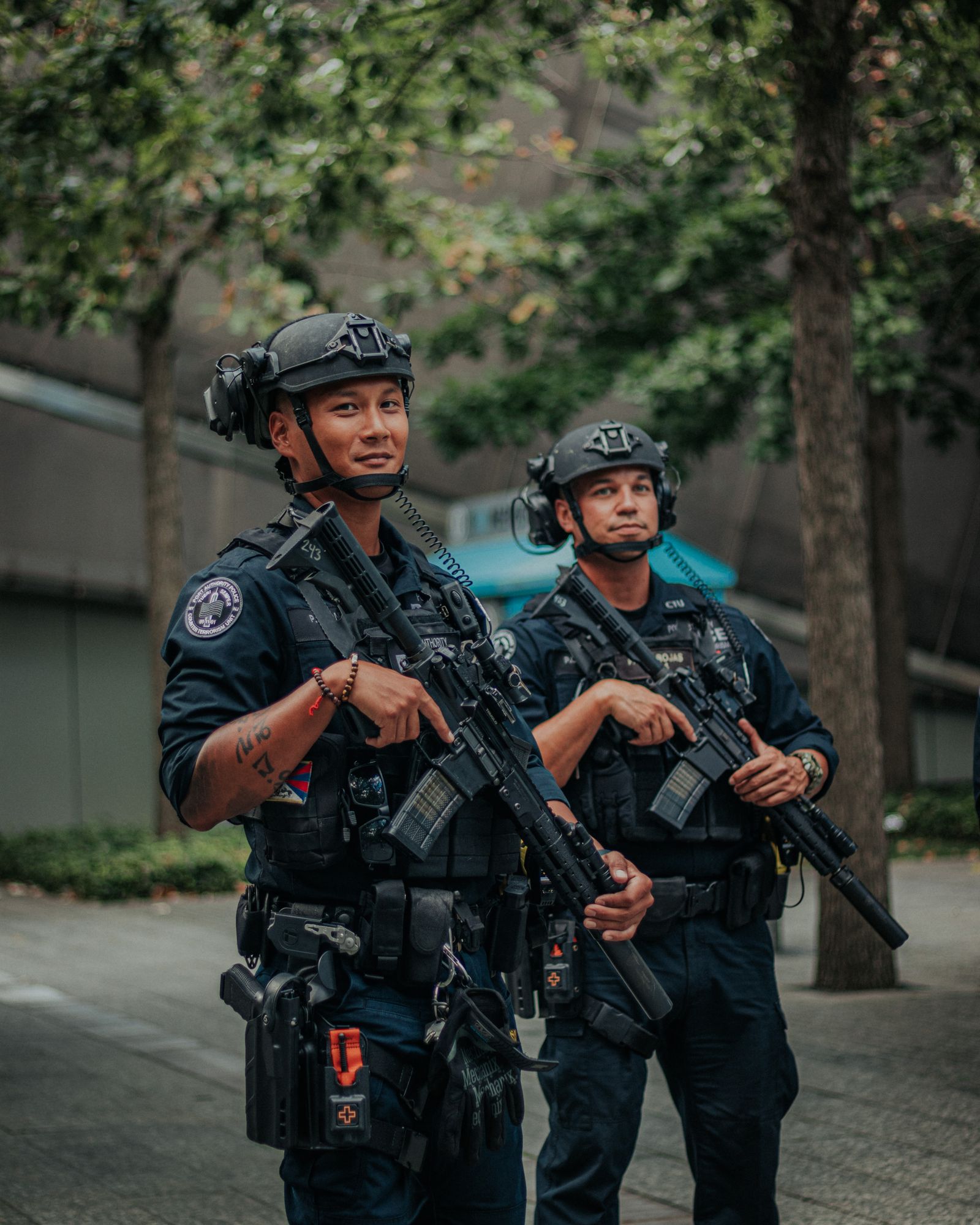 Two counter-terrorism police officers on patrol beneath city trees