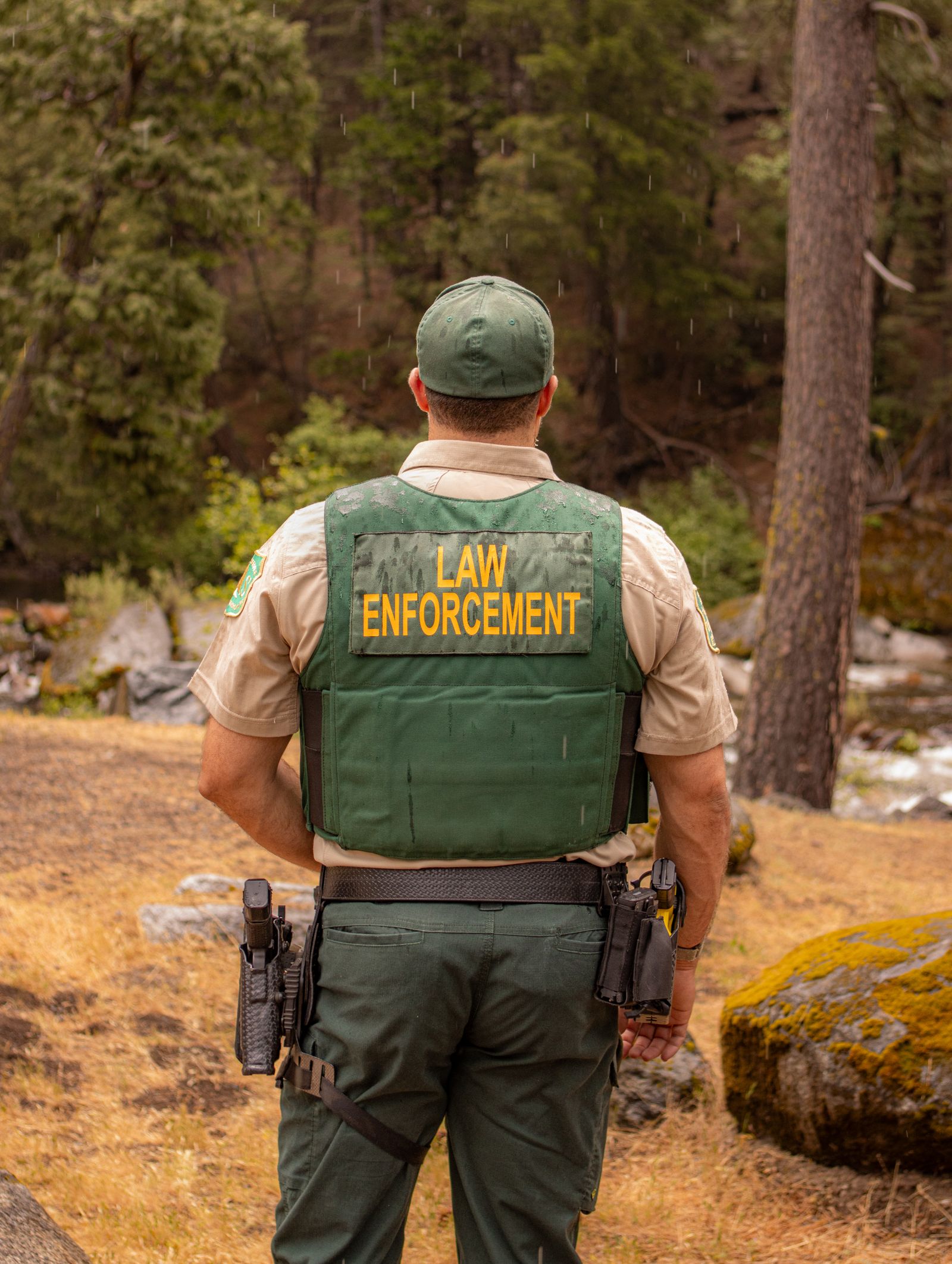 A law-enforcement ranger standing watch at the edge of a forest