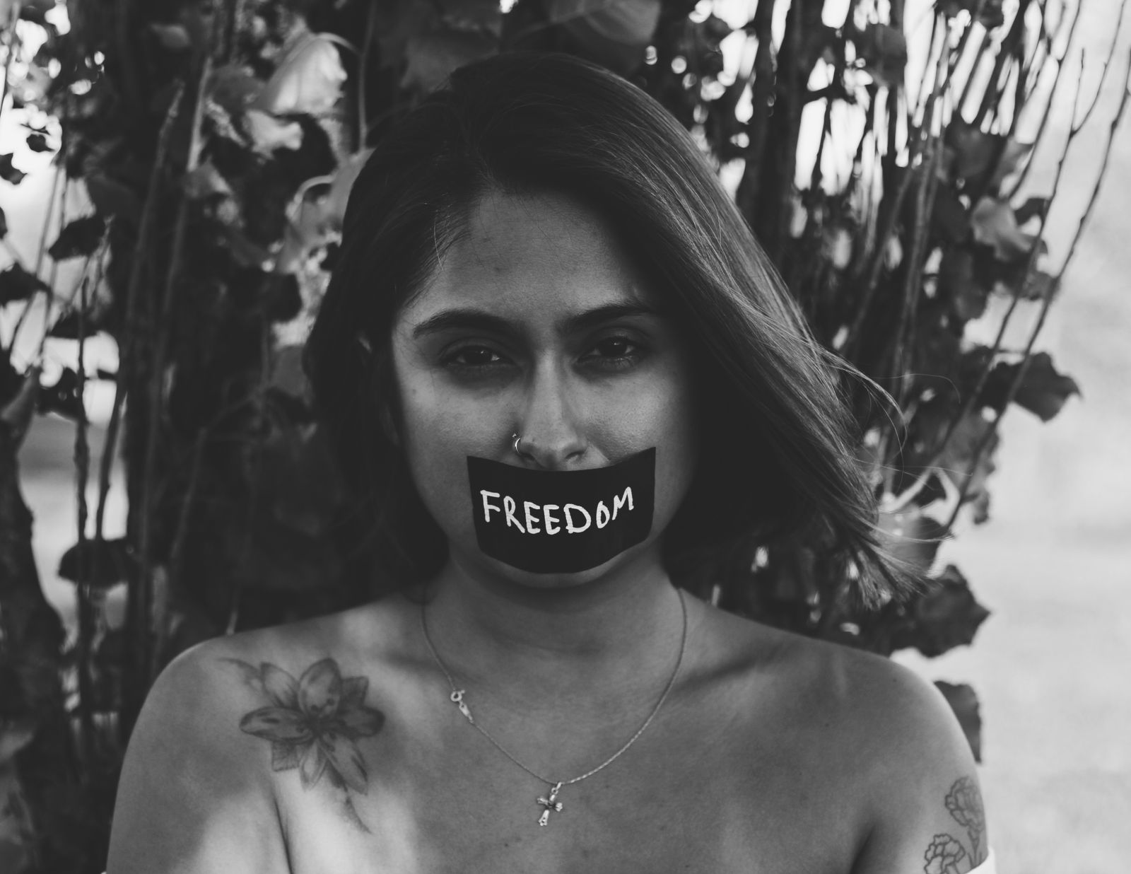 A woman with tape over her mouth reading FREEDOM