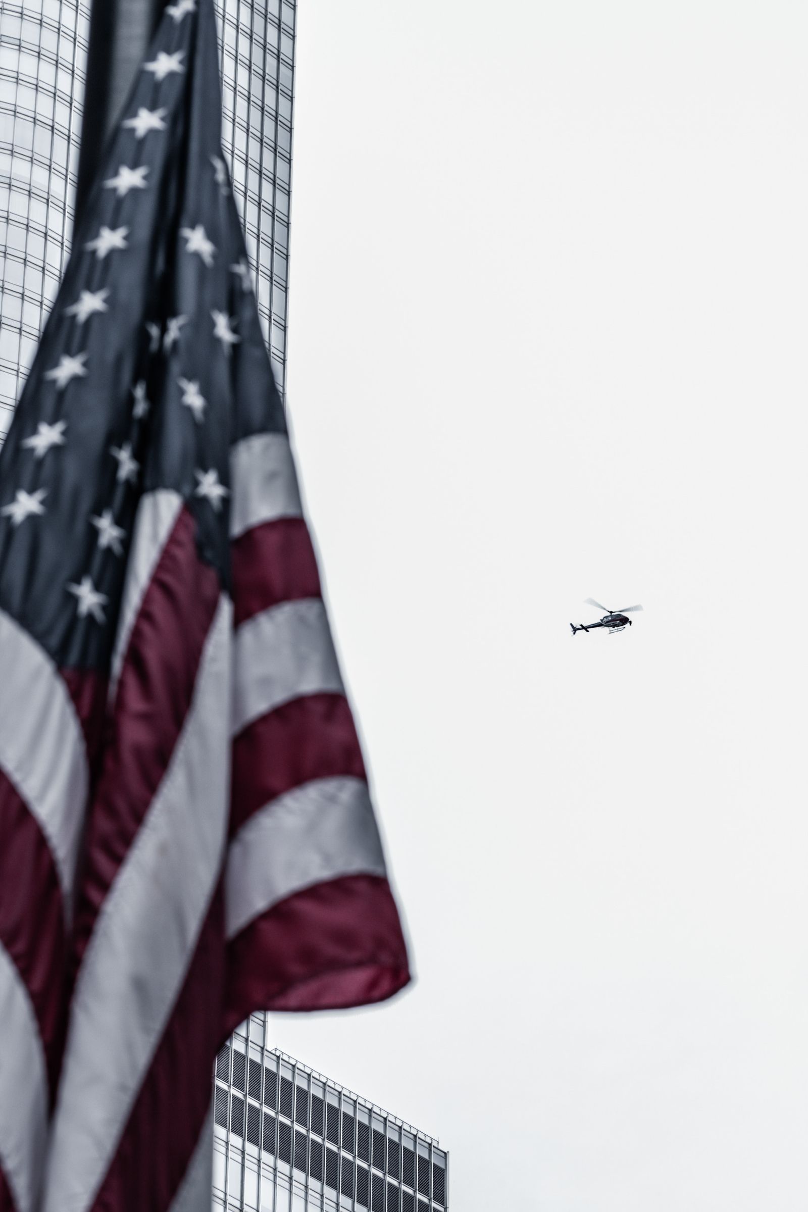 An American flag in the foreground as a helicopter passes in the distance